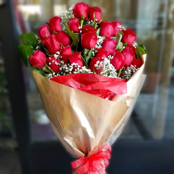 Bouquet of red roses with baby's breath wrapped in tan paper and red ribbon