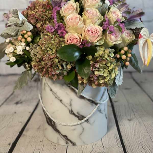 Mixed bouquet of pale pink roses and hydrangeas in a marble-patterned hat box