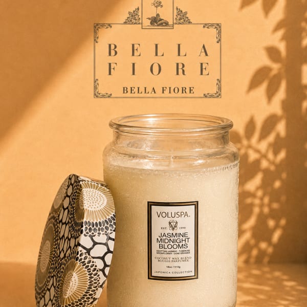 Glass jar candle with a patterned lid on a warm beige background