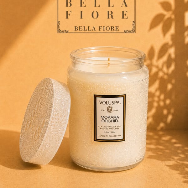 A scented candle in a textured glass jar with its lid beside it