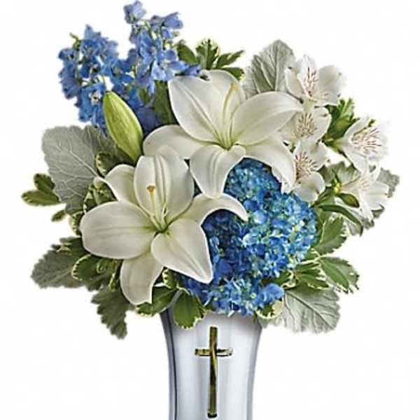 White lilies and blue flowers arranged in a silver vase