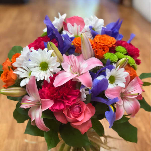 Mixed bouquet of pink, purple, orange, and white flowers in a glass vase