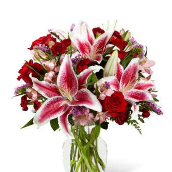 Bouquet of pink lilies and red roses in a clear glass vase