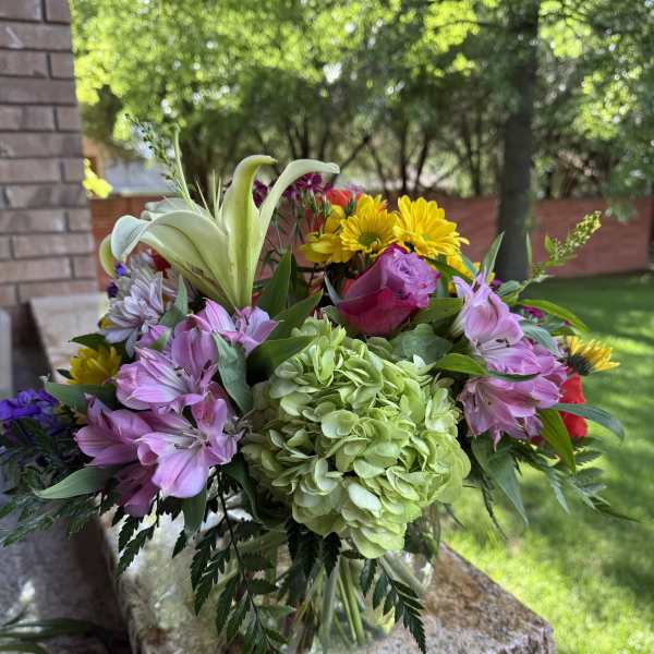 Mixed bouquet with lilies, hydrangea, roses, and daisies in a glass vase
