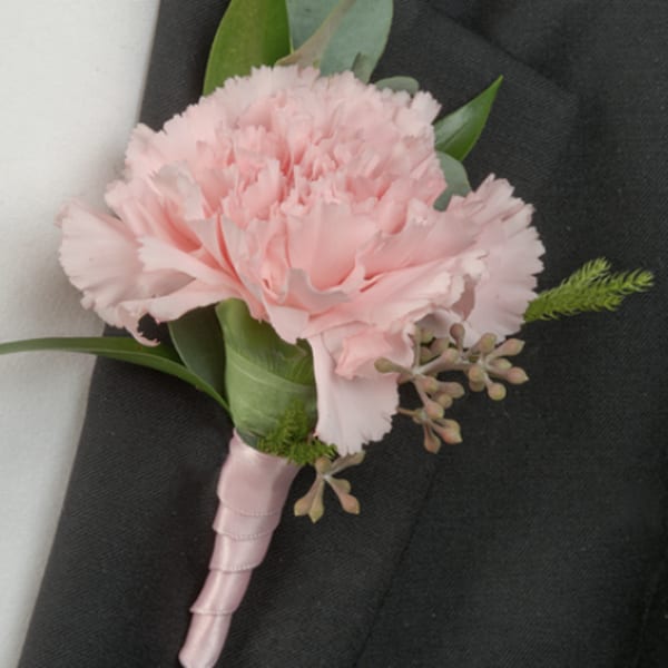 Pink carnation boutonniere with green foliage on a black suit