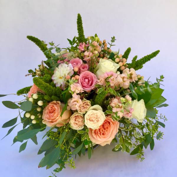 Bouquet of pink and cream roses with greenery and berry accents