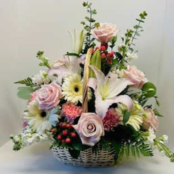 Basket arrangement of pink roses, lilies, and daisies