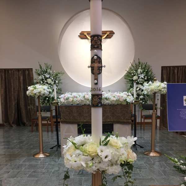 White floral altar arrangements in a church with a central cross