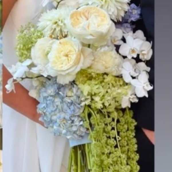 Wedding bouquet of white and pale blue flowers with trailing green blooms