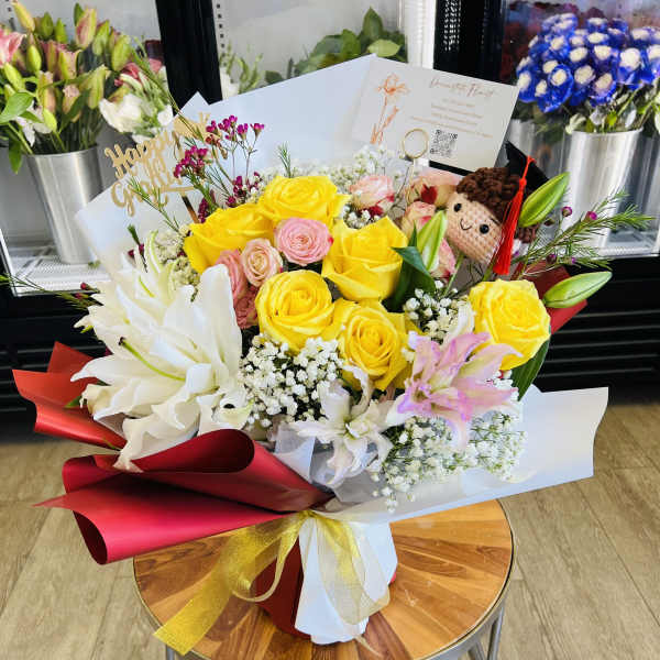 Bouquet of yellow and pink roses with white lilies and a small plush doll