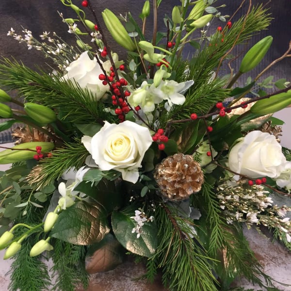 Holiday floral arrangement with white roses, lilies, and pine branches