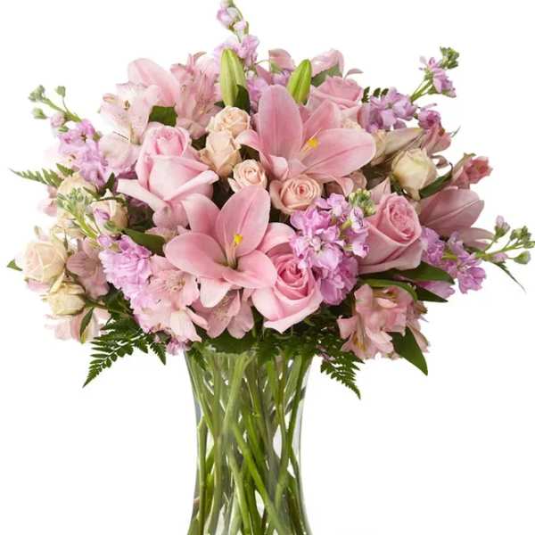 Pink roses and lilies arranged in a clear glass vase