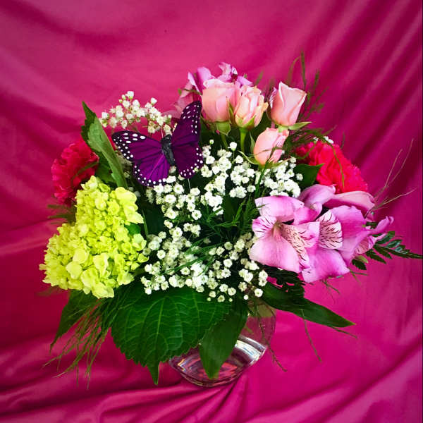 Mixed bouquet of pink roses, lilies, and baby’s breath in a glass vase