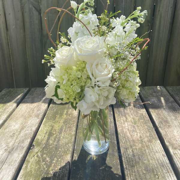 White roses and hydrangeas arranged in a clear glass vase