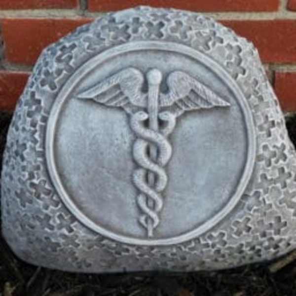 Gray memorial stone with a caduceus emblem in front of a brick wall