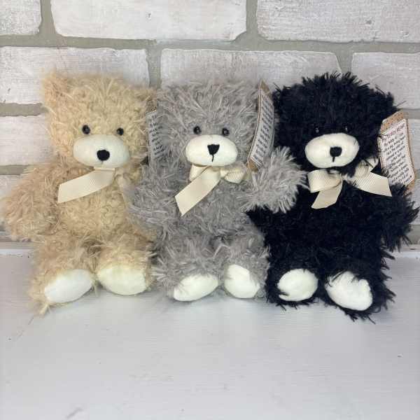Three plush teddy bears in beige, gray, and black with ribbon bows