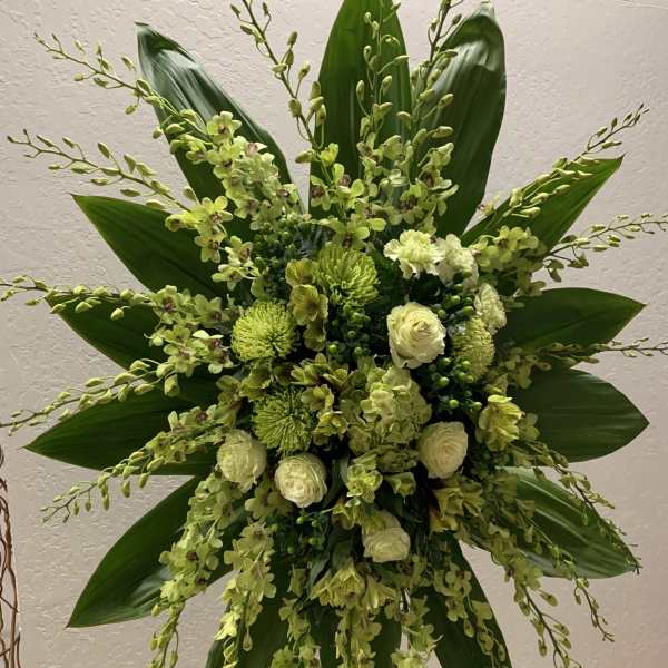 Large green floral spray with orchids and roses on a stand