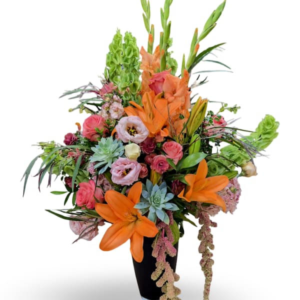 Tall mixed bouquet with orange lilies, pink roses, and green blooms in a black vase