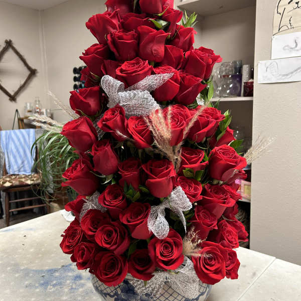 Tall arrangement of red roses in a blue-and-white ceramic vase