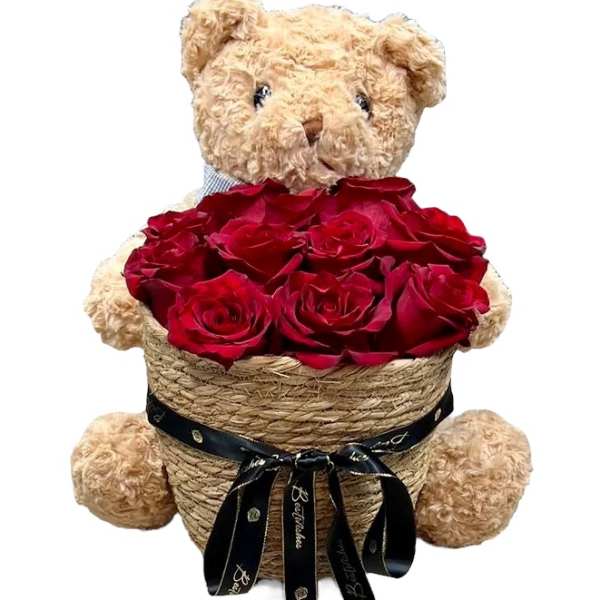 Teddy bear holding a basket of red roses