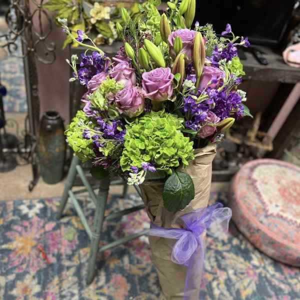 Bouquet of pink roses, purple flowers, and green hydrangeas wrapped in paper