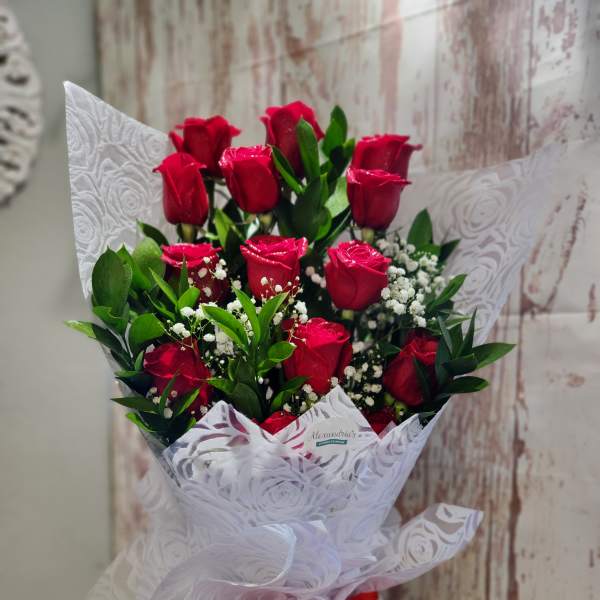 Bouquet of red roses with baby's breath wrapped in white paper and a red ribbon