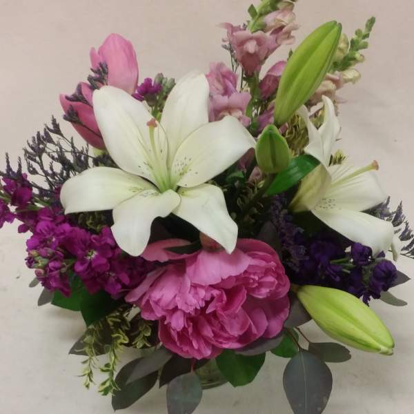 Bouquet of white lilies, pink peonies, and purple flowers in a vase