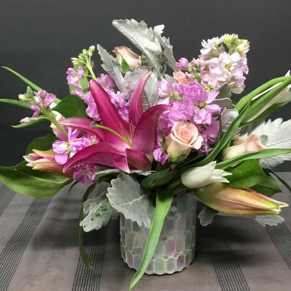 Pink lilies and roses arranged in a glass vase
