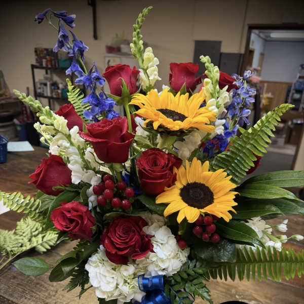 Bouquet of red roses, sunflowers, and white hydrangeas in a glass vase