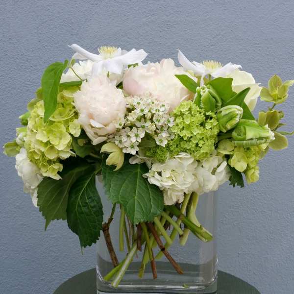 White and pale green floral arrangement in a clear glass vase