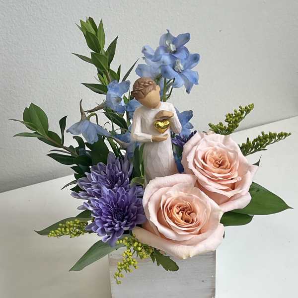 Pink roses and purple flowers in a square vase with a small angel figurine