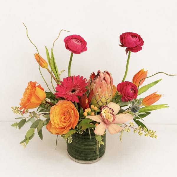 Bright mixed flower arrangement in a green glass vase