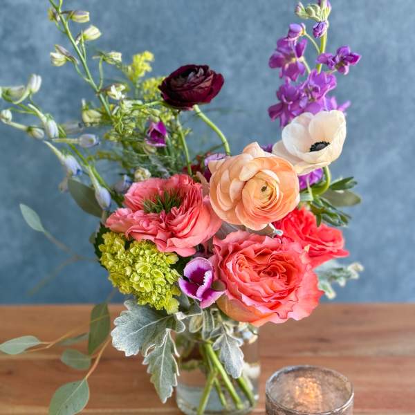 Mixed bouquet in a glass vase with pink, peach, purple, and white blooms