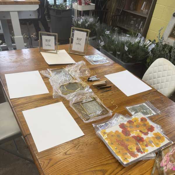 Craft supplies and framed floral pieces arranged on a wooden table