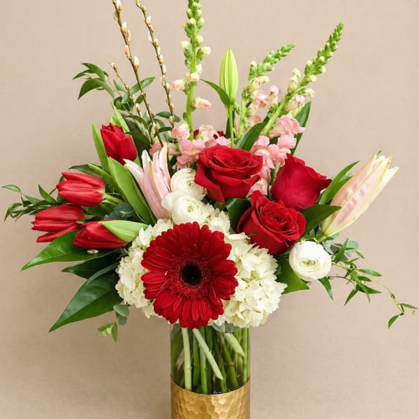 Red roses, tulips, and a gerbera daisy in a gold vase