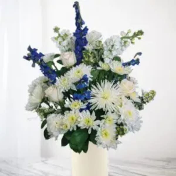 White and blue flower arrangement in a cream vase