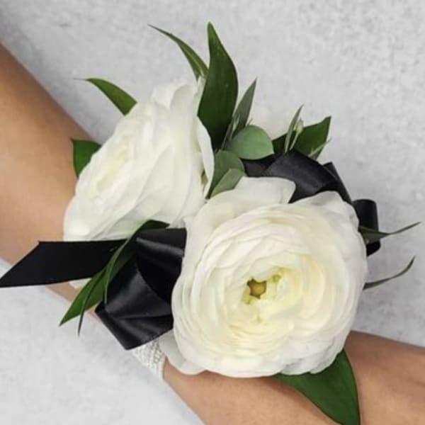 White ranunculus wrist corsage with black ribbon and green leaves