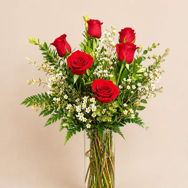 Red roses and white filler flowers in a clear glass vase