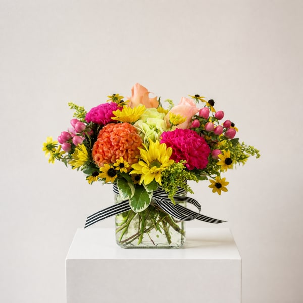 Mixed bouquet in a glass vase with pink, yellow, orange, and peach flowers