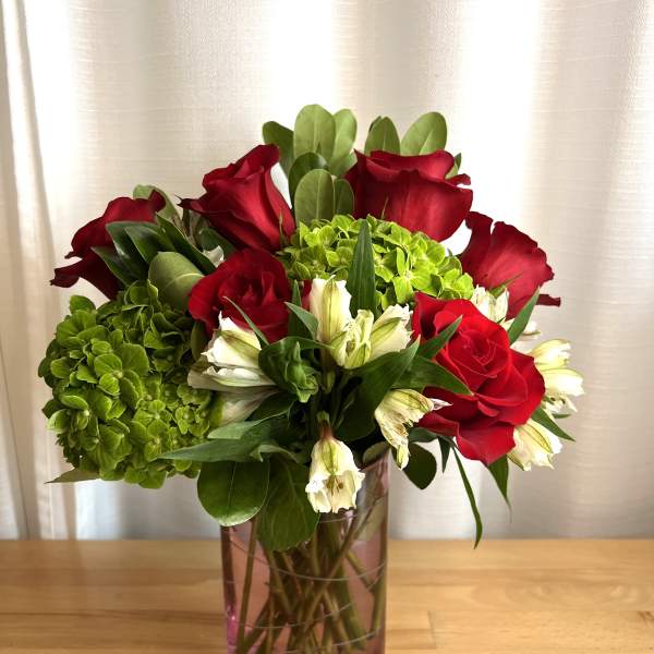 Red roses and green hydrangeas in a glass vase