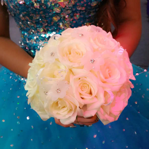 Woman in a blue sequined dress holding a pale pink and white rose bouquet