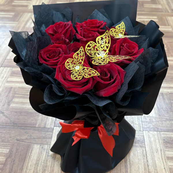 Bouquet of red roses wrapped in black paper with gold butterfly accents