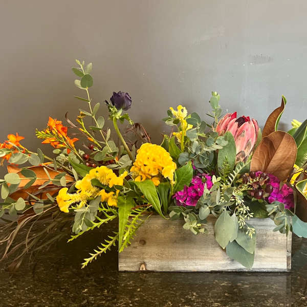 Mixed floral arrangement in a wooden box with yellow, pink, orange, and white blooms