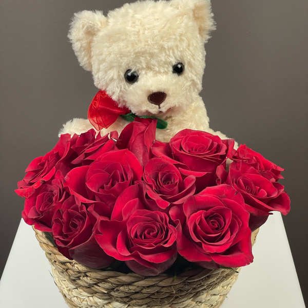 White teddy bear in a basket of red roses