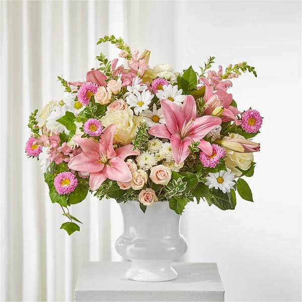 Pink lilies and mixed flowers arranged in a white vase