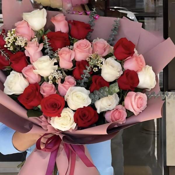 Large bouquet of red, pink, and white roses wrapped in pink paper
