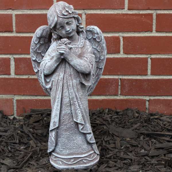 Stone angel statue standing in front of a brick wall