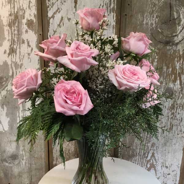 Pink roses arranged in a clear glass vase with white filler flowers