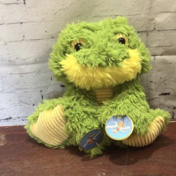 Green plush frog toy with yellow accents sitting on a table