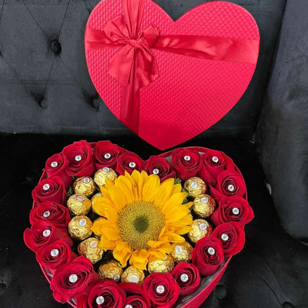 Heart-shaped gift box with red roses, a sunflower, and chocolates